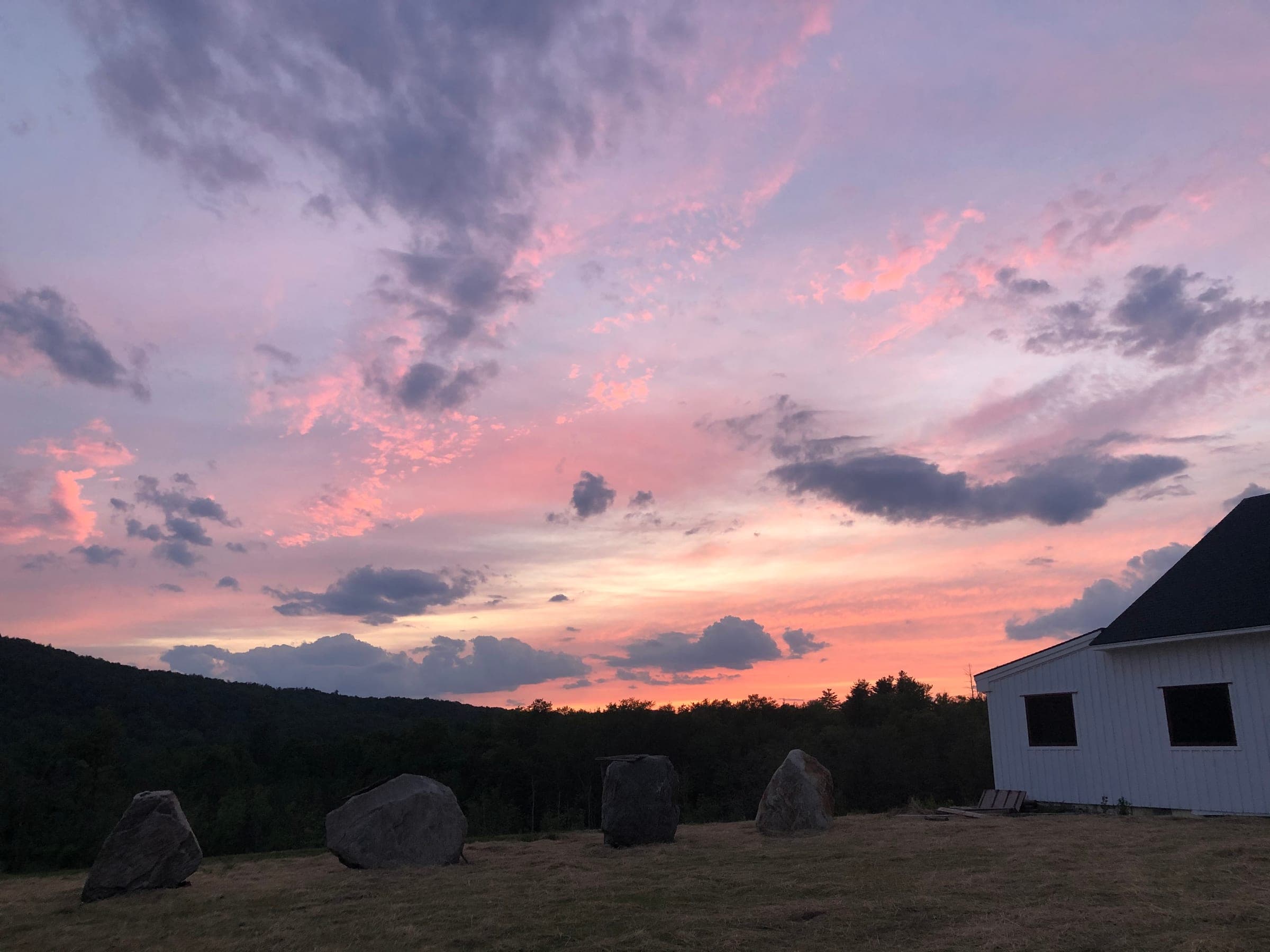 Sunset over the Vermont warehouse, pink and purple sky above the wooded hillside